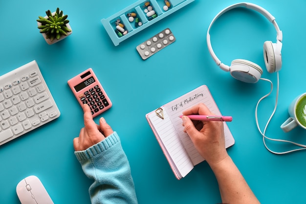 Plano creativo con un cuaderno en las manos para escribir los costos de los medicamentos.