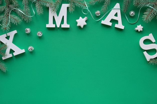 Foto plano creativo de navidad yacía con grandes letras blancas navidad en textil verde, espacio de copia. ramitas de abeto decoradas con estrellas, bolas de discoteca espejo.