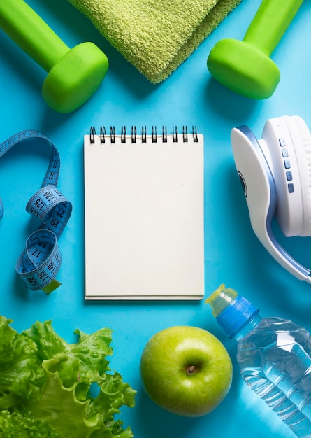 Foto plano de dieta, menu ou programa, roleta, água, halteres e frutas frescas, alimentação dietética em um fundo azul, o conceito de perda de peso e desintoxicação, vista de cima