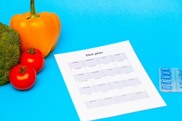 Plano de dieta, para pílulas de perda de peso e legumes frescos em azul.