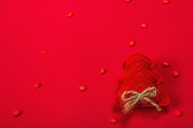 Plano de fundo de ano novo ou Natal. Pinheiro de crochê feito à mão, flocos de neve doces sobre fundo vermelho áspero. Design minimalista monocromático, disposição plana