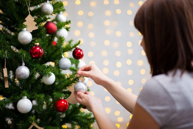 Plano de fundo de Natal - vista traseira da menina decorando a árvore de Natal em casa