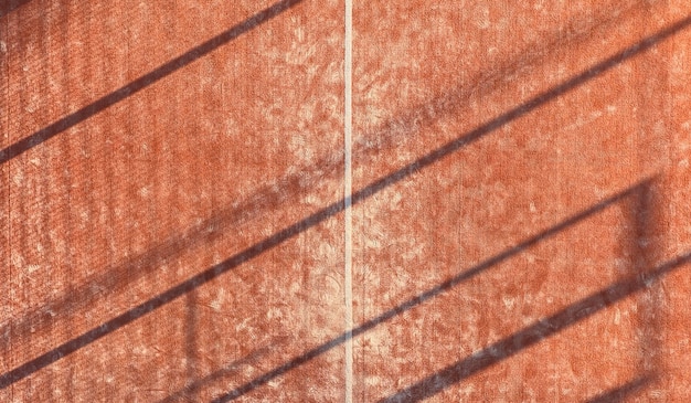 Plano de fundo de um campo de padel ao ar livre visto de cima. Quadra laranja com linhas brancas.