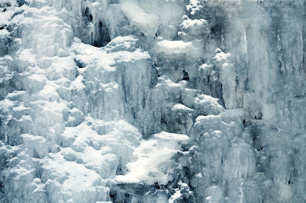 Plano de fundo de uma cachoeira de montanha congelada. Paisagem de inverno, sombras frias, rochas cobertas de neve e gelo