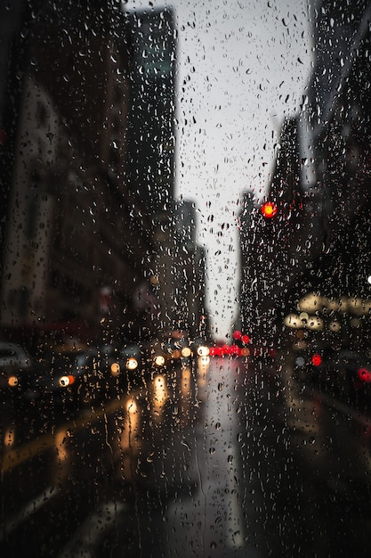 Foto plano de fundo desfocado da rua de nova york com gotas de água, luzes e carros na noite de chuva