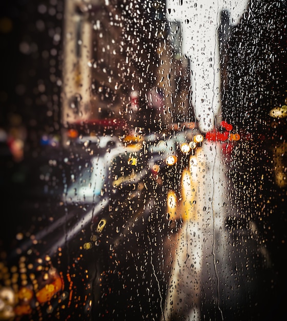 Plano de fundo desfocado da rua de Nova York com gotas de água, luzes e carros na noite de chuva