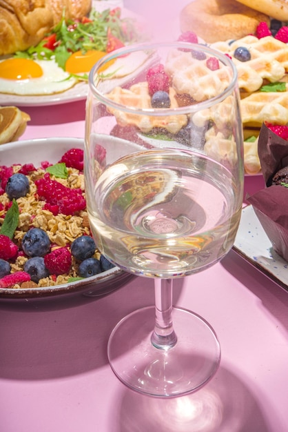 Plano de fundo do menu de brunch de dia dos namorados com vários pratos de café da manhã e almoço, waffle, croissant, muffins, donuts, frutas vermelhas, batatas fritas, ovos mexidos, panquecas, espaço de cópia de fundo rosa