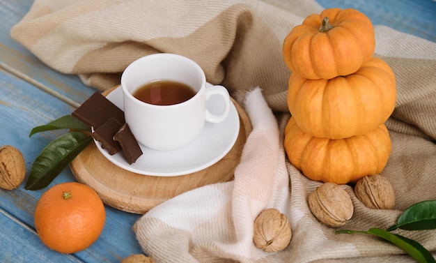 Plano de fundo liso do outono. Abóboras, maçãs, nozes, folhas, xícaras e camisola em fundo de madeira.