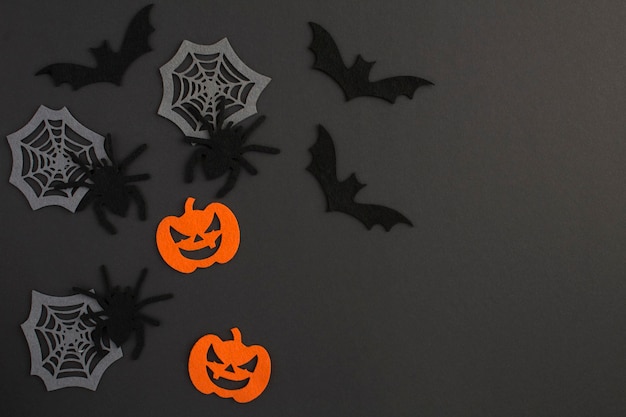 Plano de fundo para o Halloween. Aranhas decorativas, abóboras, teias de aranha e morcegos no fundo preto. Copie o espaço. Vista do topo.