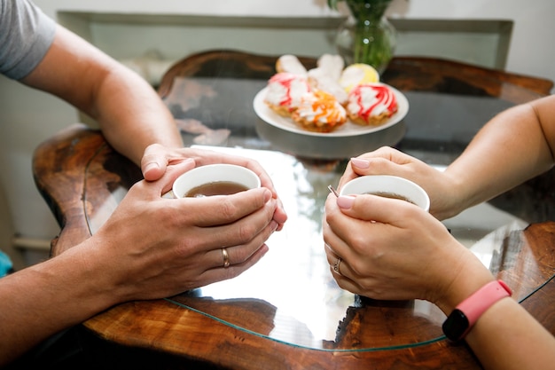 Plano de fundo romântico, duas xícaras de café e as mãos do casal apaixonado num encontro. jantar romântico no dia dos namorados