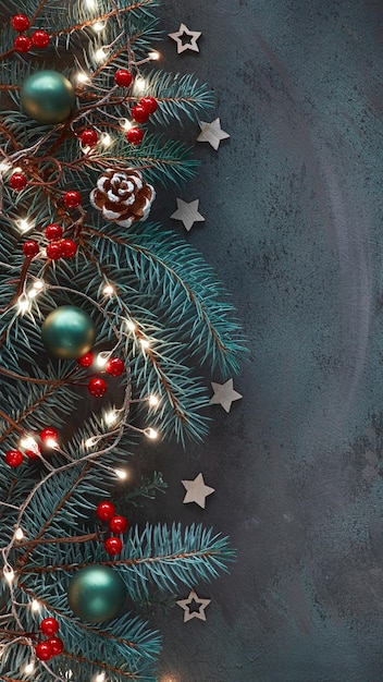 Plano de fundo vertical de Natal para histórias de mídia social Plano escuro sobre galhos de abeto, cones de bagas vermelhas e guirlanda de luz