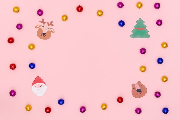 Plano de Natal com bombons de chocolate, estrelas decorativas, floco de neve, Papai Noel e árvore de Natal em papel rosa