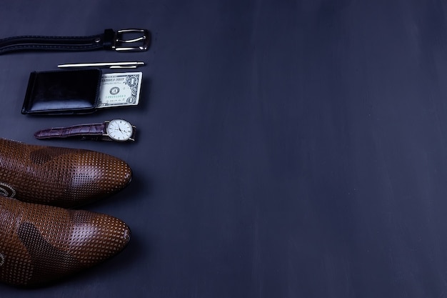 Foto plano de negócios plano de fundo com um espaço de cópia. sapatos masculinos, carteira de relógio de pulso, cinto, celular e uma gravata em fundo preto.