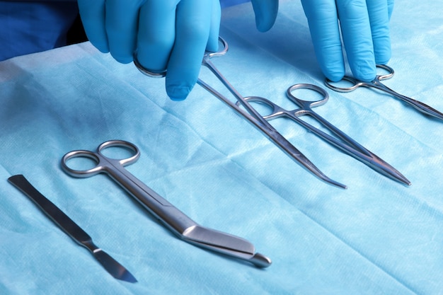 Plano de detalle de instrumentos de cirugía esterilizados con una mano agarrando una herramienta