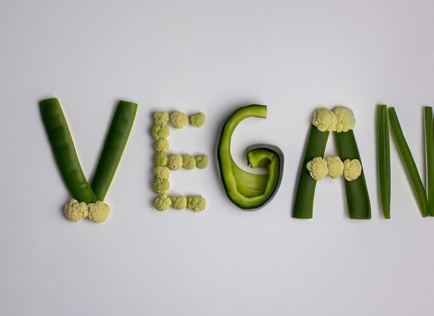 Foto plano em forma de coração e sacola de compras e compras curto fundo vegano e logotipo vegano arranjo vegetal letras veganas feitas de vegetais em fundo branco