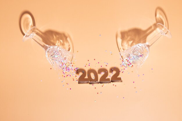 Plano festivo de año nuevo con números 2022 y sombras duras con gafas y decoración brillante