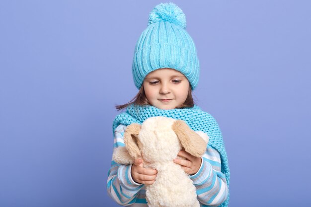 Plano horizontal de la niña sosteniendo su juguete de perro suave en las manos y mirándolo