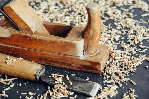 Plano de mano antiguo y cincel con virutas de madera sobre fondo negro. Antigua herramienta de mano para trabajar la madera. Copiar, espacio vacío para texto