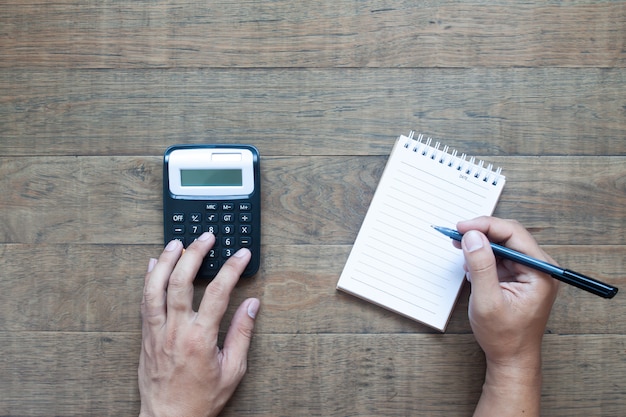 Plano de la mano del hombre que calcula presupuesto con nota de papel.