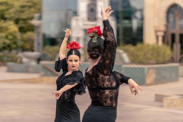 Plano medio de 2 bailarinas de flamenco jóvenes con un piercing en la nariz bailando en una plaza