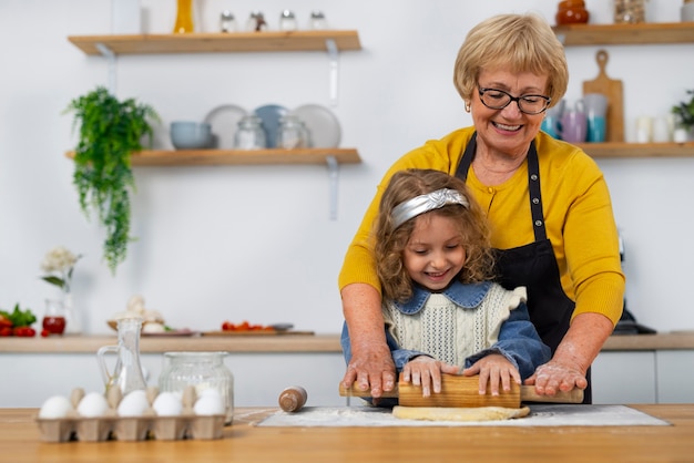 Foto plano medio anciana y niña en la cocina