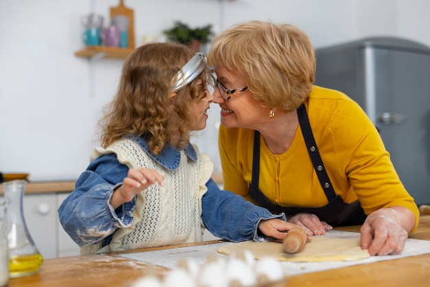 Foto plano medio anciana y niña en la cocina