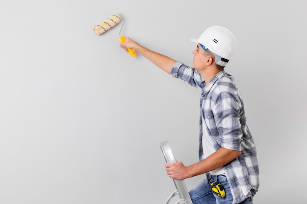 Foto plano medio del hombre que sostiene un rodillo de pintura con espacio de copia