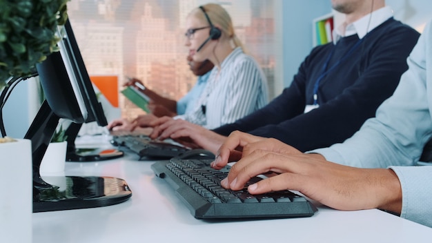 Plano medio de las manos de los operadores escribiendo en el teclado en la oficina moderna