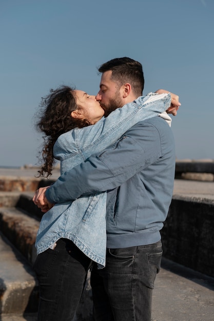 Plano medio pareja besándose al aire libre