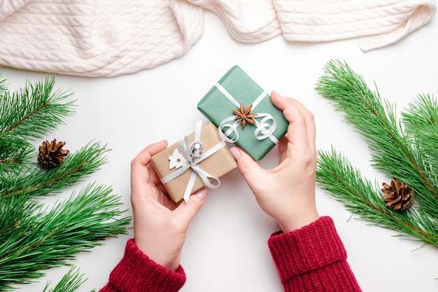 Plano de Navidad sentar con manos femeninas sosteniendo cajas de regalo de Navidad decoradas en blanco