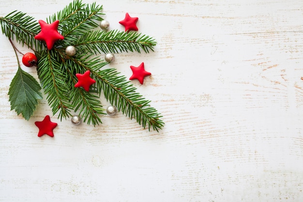 Plano de Navidad sentar con una rama de abeto verde, estrellas rojas y bayas, y perlas blancas sobre blanco