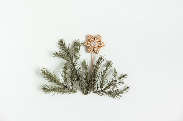 Plano de Navidad sentar con ramas de pino abeto y estrella de pan de jengibre sobre el fondo blanco.