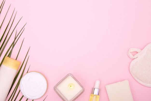 Foto plano de productos cosméticos e higiénicos y hoja de palma sobre un fondo rosa concepto de spa en casa espacio de copia de fondo de belleza