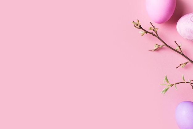 El plano rosa de pascua yacía con huevos coloridos y una rama con hojas en la vista superior del espacio de copia de fondo rosa