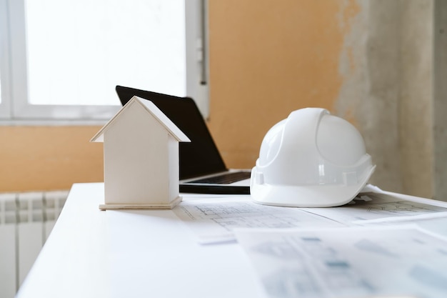 Foto los planos del casco de protección, el modelo de la casa portátil y las herramientas en el espacio de trabajo del arquitecto en el sitio de construcción