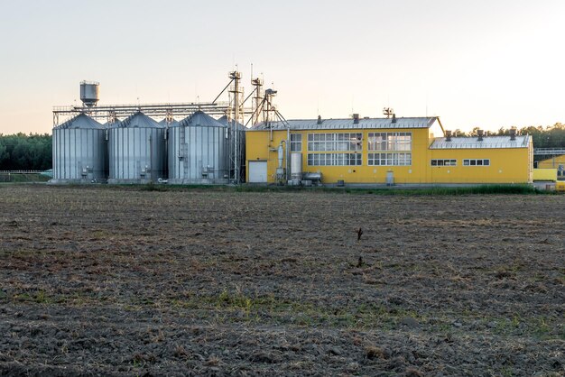 Planta de agroprocesamiento para procesamiento y silos para secado, limpieza y almacenamiento de productos agrícolas, harina, cereales y granos con hermosas nubes.