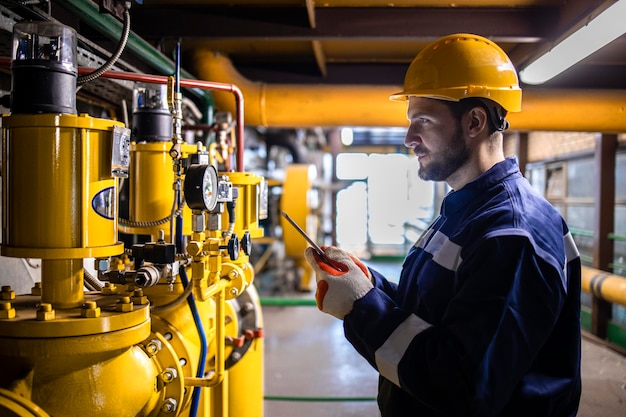 Planta de aquecimento industrial ou usina e trabalhador usando tablet e verificando instalações de gás