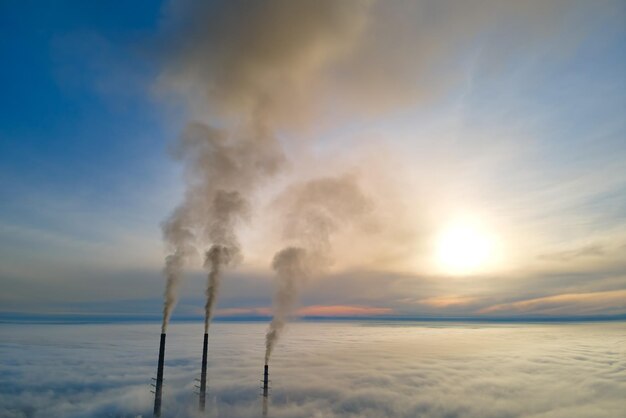 Foto planta de energía de carbón tubos altos con humo negro moviéndose hacia arriba contaminando la atmósfera producción de energía eléctrica con concepto de combustible fósil