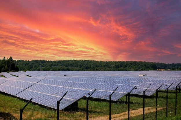 Planta de energía solar de módulos fotovoltaicos en el espectacular fondo del cielo al atardecer. Concepto de energía de energía alternativa limpia.