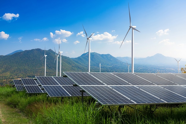 Planta de energía solar de módulos fotovoltaicos con turbinas de viento contra el paisaje de las montañas contra el cielo azul con nubes, concepto de energía alternativa, energía limpia, energía verde.