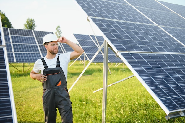 Planta de energía solar de trabajador masculino sobre un fondo de paneles fotovoltaicos