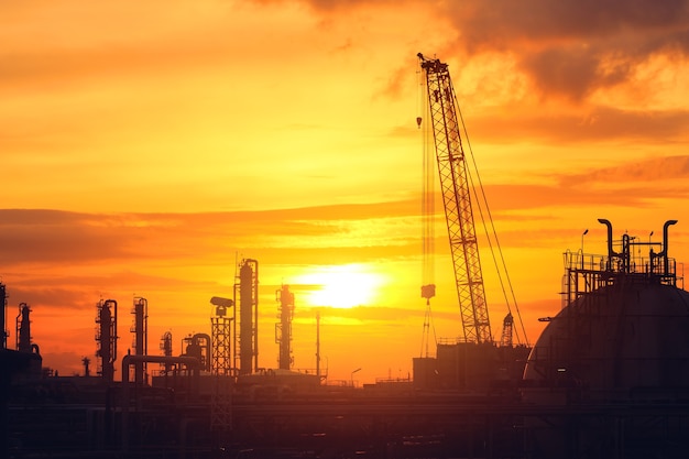 Foto planta de la industria del petróleo con cielo al atardecer, imagen de silueta de planta industrial petroquímica