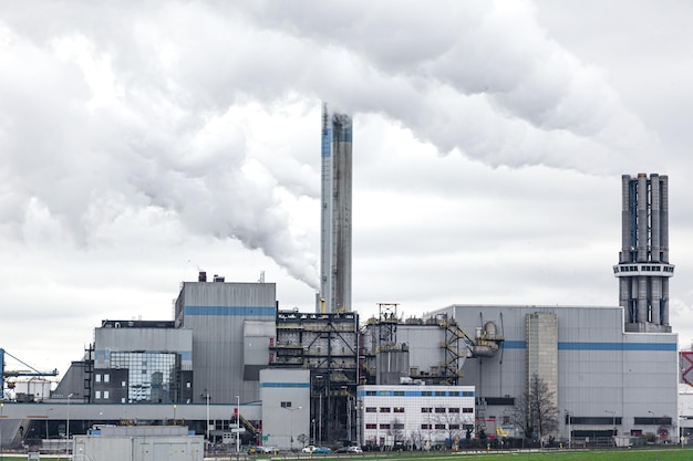 Una planta industrial con tubos de escape de los que sale humo espeso hacia el cielo nublado