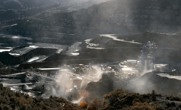 Planta minera en cantera de piedra en nubes de polvo de producción paisaje espectacular retroiluminado con bengala solar