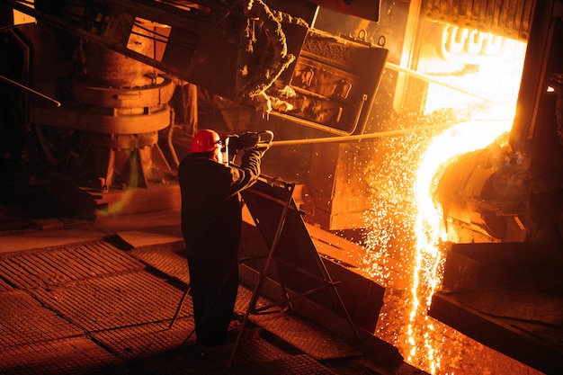 Planta para la producción de acero. Un horno de fusión eléctrico. El obrero toma una muestra de metal.