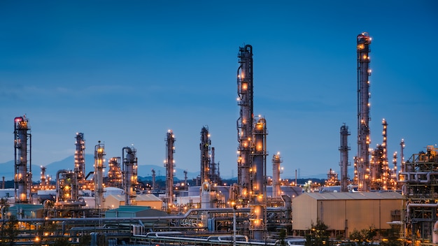 Planta de refinería de petróleo y gas o industria petroquímica en el fondo del crepúsculo del cielo azul, fabricación de petróleo industrial