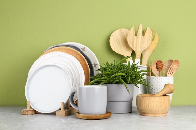 Planta verde y diferentes utensilios de cocina en la mesa cerca de la pared de color Diseño interior moderno