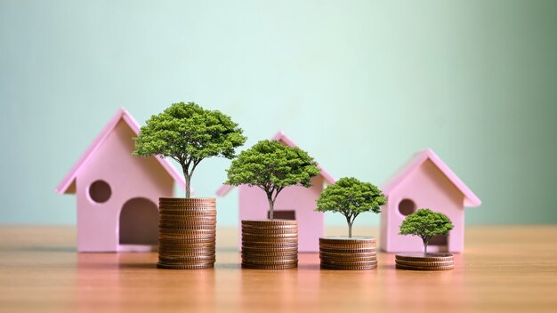 Las plantas que crecen sobre montones de monedas y modelos de casas simulan ideas de inversión inmobiliaria. préstamos hipotecarios y tasas de interés para viviendas