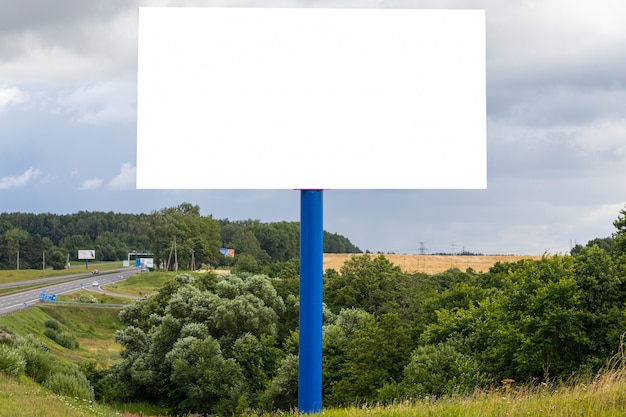 Plantilla de cartelera en blanco blanco a lo largo de la carretera contra campos