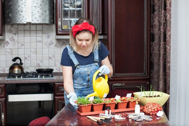 Plántulas de primavera. Niña cultiva plántulas de hierbas en la cocina de la casa.